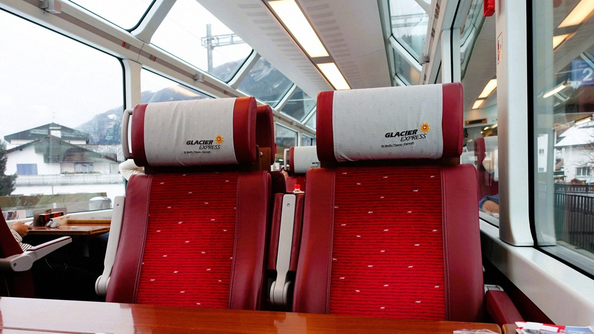 Interior of a Glacier Express panoramic coach with red seats and large windows