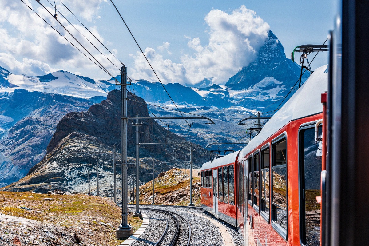 A red Gornergrat Railway train travels above Zermatt with the Matterhorn in view